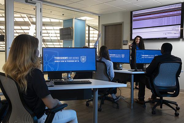 cybersecurity students in a computer lab listening to an instructor